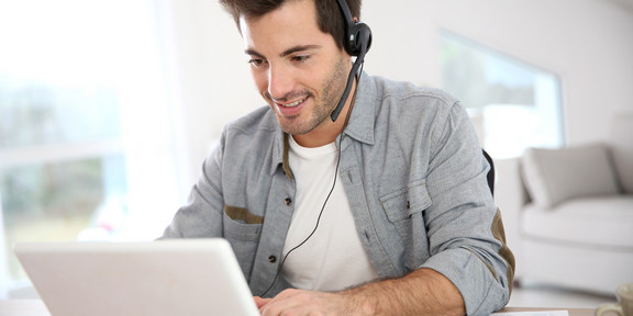 Man in video conference Man sits in front of the laptop and has a headset on.